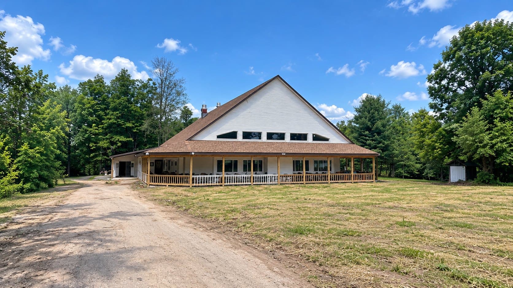 A shul with a steep gabled front and a band of clerestory windows, a covered porch wrapping the building