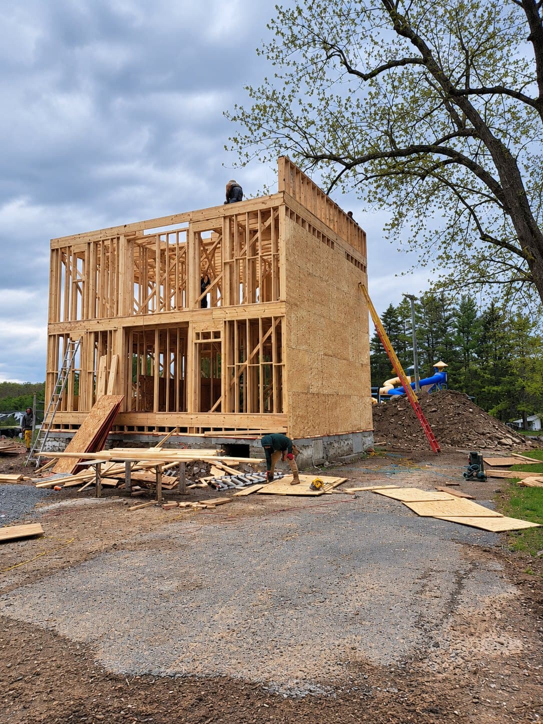 A two-storey timber frame standing on its foundation, sheathing on the lower walls and the upper floor open to the sky
