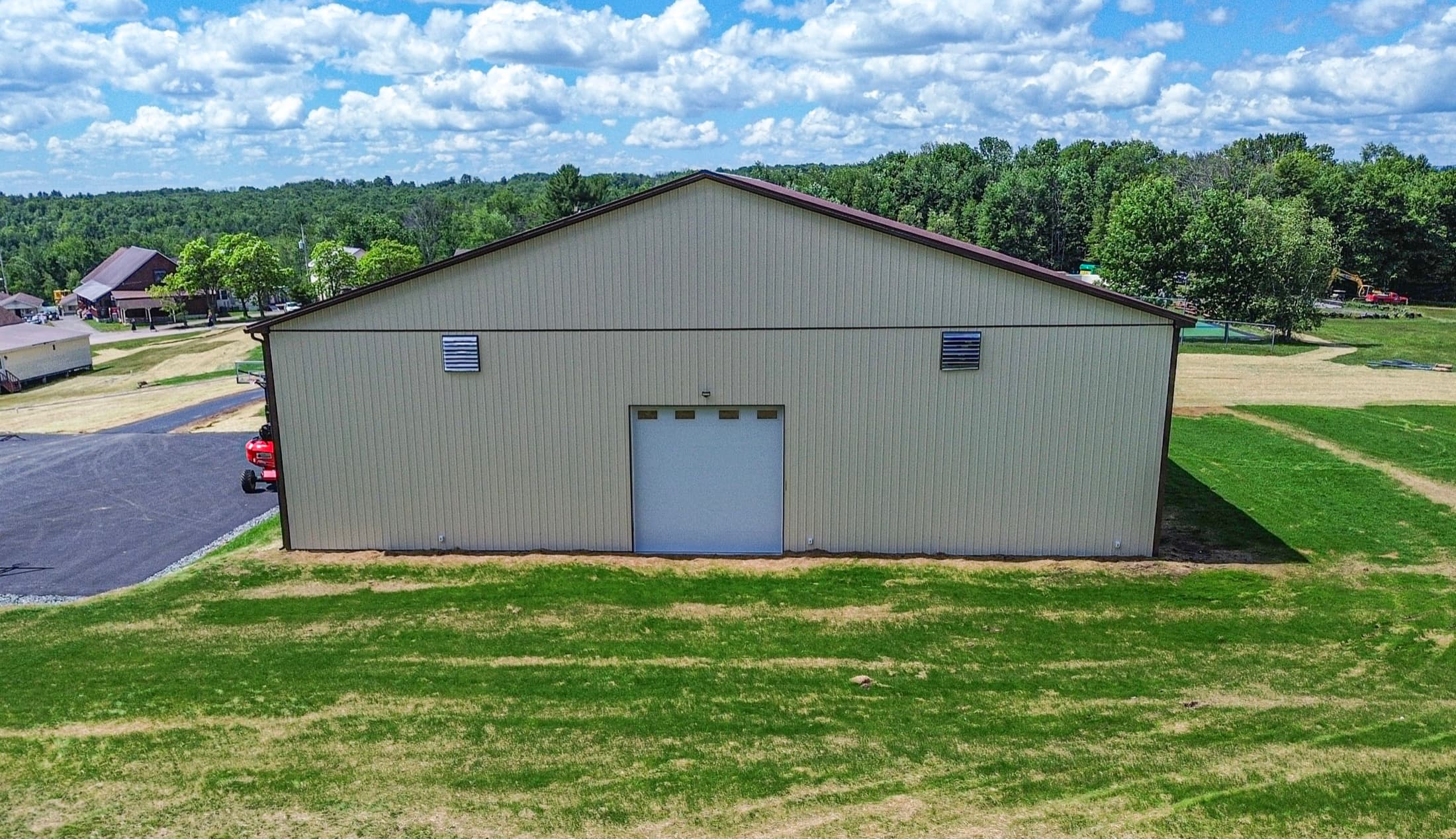 A wide-span recreation building from outside, steel roof and clear-span walls on open ground