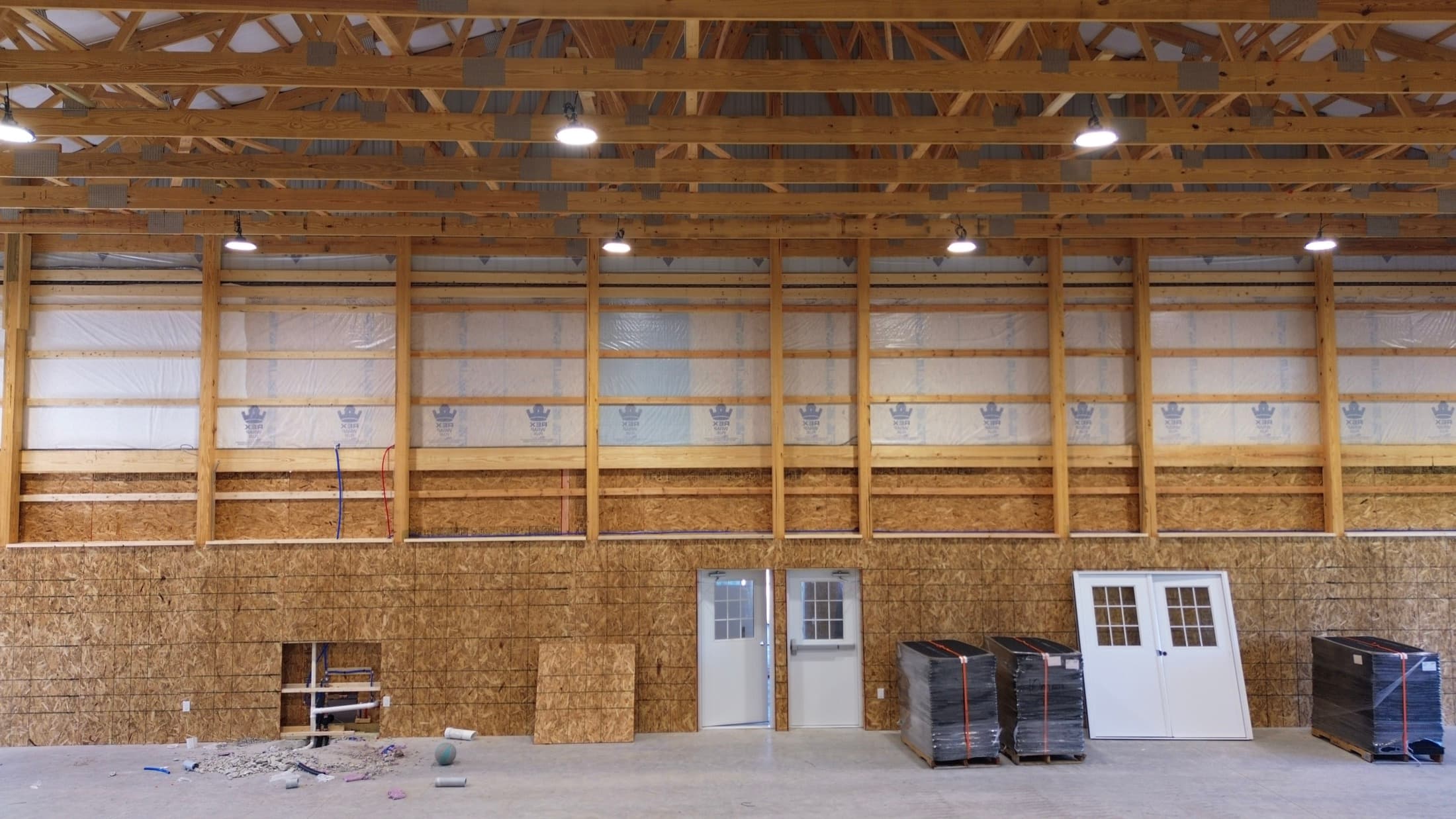 Inside a recreation building, timber framing and clerestory windows above an uninterrupted concrete slab