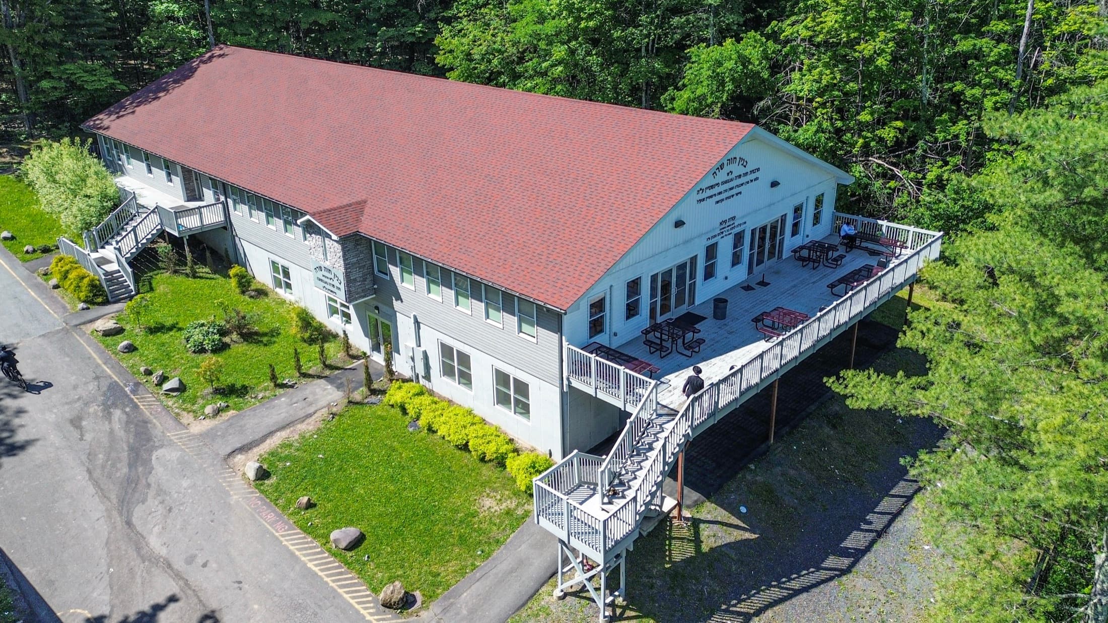 Aerial view of a completed shul, red roof, a full-length deck and an exterior stair