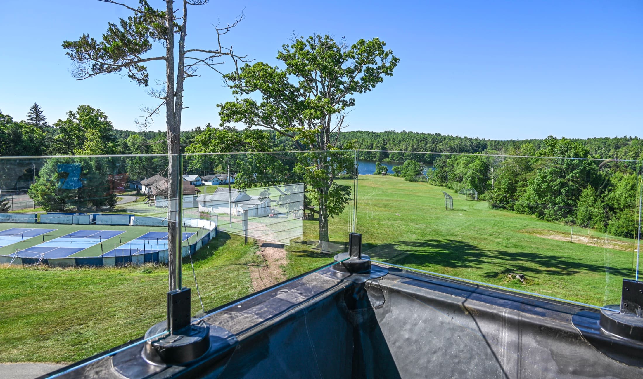 A finished roof deck with a glass balustrade, looking out over the courts, playing fields and lake